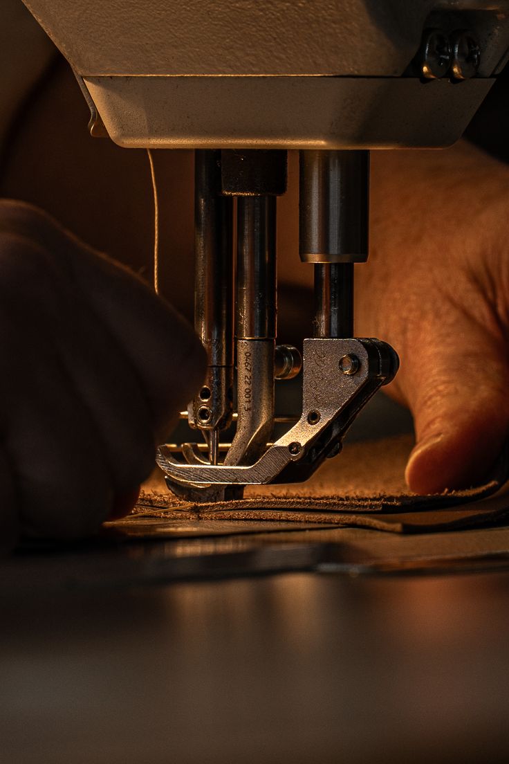 Hands guiding leather under a stitching machine